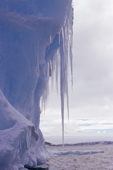 Curtains of icicles hang from a rich blue iceberg in the Antarctic summer. Antarctic Peninsula.