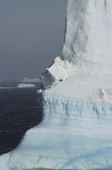 Block of ice frozen onto the side of a huge iceberg that shows the layers of ice. Antarctica.