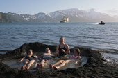 Tourists in thermal pool at Whalers Cove. Zodiac comes from Kapitan Dranitsyn. Deception Island. Antarctica