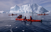 Eco tourists in double kayaks paddle amongst icebergs. Antarctica