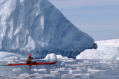 Eco tourist in single sea kayak paddles by an iceberg. Brown Bluff. Antarctica