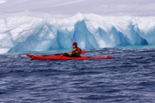 Eco tourist in single sea kayak paddles by an iceberg. Brown Bluff. Antarctica