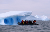 Zodiac approaches an iceberg with a dramatic blue heart. Antarctic Peninsula.