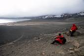 Tourists sit by Neptune's Window at Whalers Bay, and view over to the Whaling station Deception Antarctica