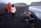Visitor to Whalers Bay tests the heat from hotsprings under the black sands. Deception Is. Antarctica