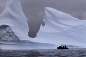 Tourist zodiac is dwarfed by the huge icebergs near Pleneau Island. Antarctic Peninsula