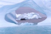 Eco tourism Zodiac seen through a hole in an iceberg near Pleneau Island. Antarctic Peninsula
