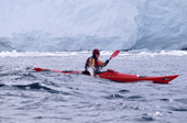Eco tourist in a sea kayak paddles past a glacier near Port Lockroy. Antarctic Peninsula