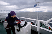 Woman tourist downloading a digital camera to a laptop computer on the deck of a tourist ship in Antarctica