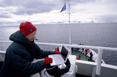Silver surfer downloading a digital camera to a laptop computer on the deck of a tourist ship in Antarctica