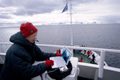 Silver surfer downloading a digital camera to a laptop computer on the deck of a tourist ship in Antarctica