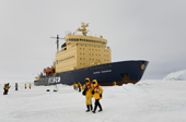 Russian Icebreaker Kapitan Khlebnikov parked in the sea ice in Antarctica with tourists walking around.