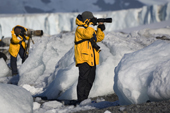 Enthusiastic photographers stand amongst ice blocks to photograph on Brown Bluff Beach. Antarctica