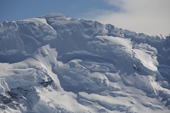 Dramatic cornices top a mountain slope that bulges with ice and glaciers. Gerlache Strait. Antarctic Peninsula.