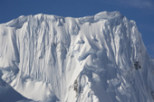Dramatic cornices top a mountain peak that hangs with ice and glaciers. Gerlache Strait. Antarctic Peninsula.