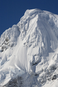 Dramatic cornices top a mountain peak that hangs with ice and glaciers. Gerlache Strait. Antarctic Peninsula.