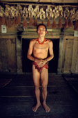 Mentawai medicine man in a longhouse. Above him monkey skulls. Siberut. Indonesia.