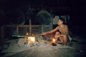 A Mentawai man bakes sago in bamboo sticks over a fire. Siberut. Indonesia
