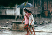 Children walking through the monsoon rains. Sumatra. Indonesia.