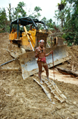 Mentawai medicine man stands on broken bulldozer in his rainforest. Indonesia.