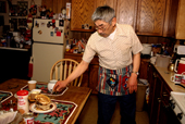 Clifford Weyiouanna, an eskimo elder, serves hotcakes in his kitchen . Shishmaref. Alaska. 2003