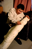 Eskimo sculptor, Jimmy 'Ataata Boo' Weyiouanna working on a large whale bone carving in his home. Shishmaref. Alaska. 2003