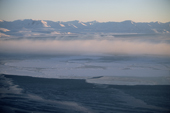 Bands of frost smoke hang over open water and new sea ice off Wales on the Bering Strait. Alaska. 2003