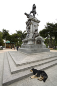A dog sleeps by the statue in the Plaza Muoz Gamero , when no one comes to touch the toe of Magellan's indian. Punta Arenas. Chile.