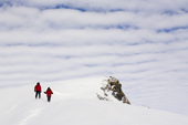 Andy and Denise walk down a snow slope to Windy Ridge, with 'altocumulus undulatus' above them. Patriot Hills. West Antarctica