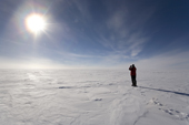 Sun shining over the Polar Plateau at 89 degrees South. Man with camera will ski the Last Degree to the South Pole. Antarctica.