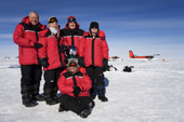 A group of visitors to the South Pole pose by the Ceremonial Pole. Antarctica