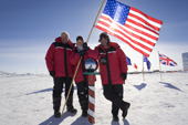 Three American visitors to the South Pole pose by the Ceremonial Pole. Antarctica