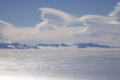 Two snowmobiles on the blue ice in front of the Ellsworth Mountains, with Orographic clouds. Antarctica