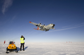 C130 equipped with skis flies over a groomed skiway prior to landing at Patriot Hills. ALE staff on the threshold. Antarctica
