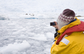 Tourist in a zodiac photographs a Leopard seal asleep in the ice.