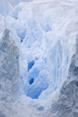 A crevasse leads deep int the face of a glacier revealing ice bridges and cold blue shadows. Cierva Cove. Antarctica