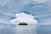 Zodiac seen through an ice arch in an iceberg, cruising near Pleneau Island. Antarctica
