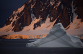 Iceberg in Marguerite Bay. Sunset catches the ice cliffs behind it. Antarctica