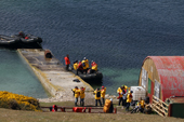 Yellow jacketed tourists ready to board a zodiac on the jetty at West Point Island. The Falklands