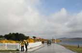 Tourists in yellow jackets check a map while on the shore road in Stanley, Capital of the Falkland Islands
