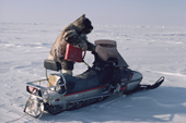 An Inuit hunter re-fuels his snowmobile during a journey. Igloolik, Nunavut, Canada. 1987