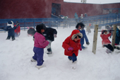 Inuit children play outside in a blizzard during a school recess. Igloolik, Nunavut, Canada. 1995
