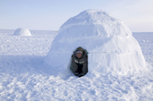 An Inuit boy at the entrance to an Igloo built out on the frozen sea near Igloolik. Nunavut, Canada. 2008