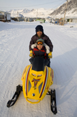 Two Inuit boys driving a child size snowmobile in Pangnirtung. Nunavut, Canada. 2008