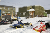 Brightly coloured snowmobiles outside Inuit hunters' homes in the community of Pangnirtung. Nunavut, Canada. 2008
