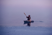 Louis Tepardjuk, paddling a floe edge boat through frost smoke while seal hunting at the ice edge near Igloolik, Nunavut, Canada. 1990