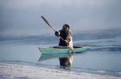 Louis Tepardjuk, paddling a floe edge boat through frost smoke while seal hunting at the ice edge near Igloolik, Nunavut, Canada. 1990
