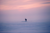 At sunset, an Inuit man checks his fish net set under the ice at Baker Lake. Nunavut, Canada. 1982