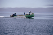 An Inuk hunter aims his rifle at a seal from the prow of a freighter canoe. Igloolik, Nunavut, Canada, 1992