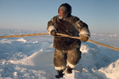Inuit hunter, Tatigat, in caribou skin clothing, works to get his dog sled over an ice ridge. Igloolik, Canada. 1993